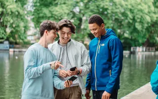 Three teenagers standing by the canal on their phones