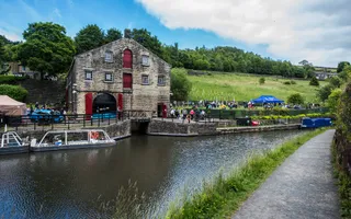 An old building with red features stands across a canal on the opposite bank, with a small tunnel entrance visible below.