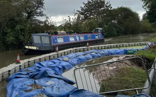 Blue narrowboat beside canal repairs