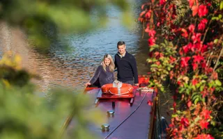 Couple on canal boat with red flowers on one side