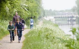 Two boys on scooters on towpath by canal
