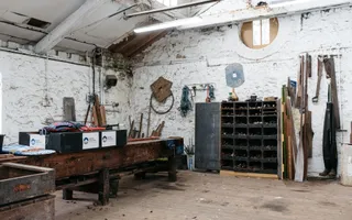 An old workshop, with an aged work bench and tools hanging on the walls.