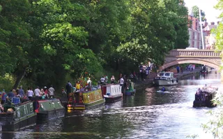 Boats moored along towpath on River Soar, with walkers passing by