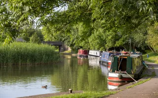 canal to the ledt and moored boats to the right with trees overhanging