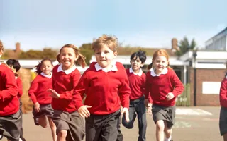 A group of school children running across the playground with smiles on their faces and a hint of competition in their eyes.