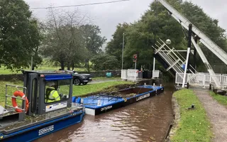 Wide shot of a canal and draw bridge with boat passing through