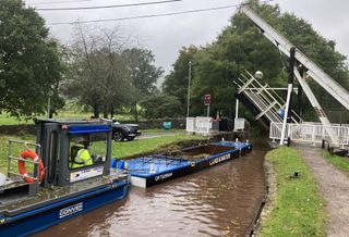 Wide shot of a canal and draw bridge with boat passing through