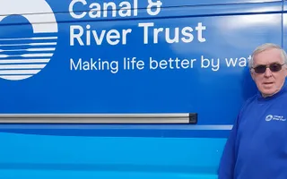 Volunteer lock keeper poses in front of a Canal & River Trust branded van