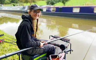 A young person sat next to the canal fishing