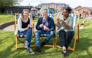 Three people sitting on deck chairs eating icecream