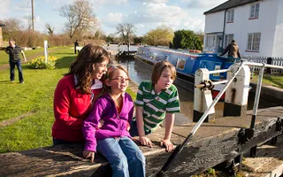 Family sitting on a lock gate watching canal boats