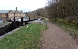 Wide shot of a canal and towpath with lock gate on the left