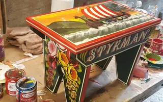 A stall painted with traditional canal Roses & Castles, picturing a Viking boat on the top.