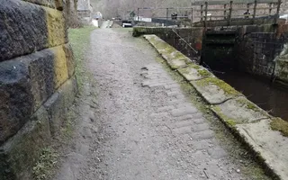 Old canal towpath with lock on the right and wall on the left
