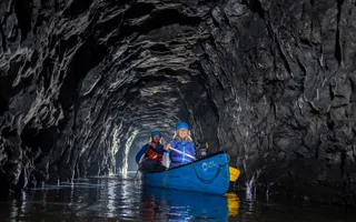 Two people in a canoe paddling inside a tunnel.