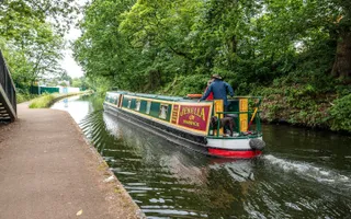 Canal boat travelling along green areas of canal