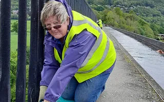 A volunteer works along the towpath on an aqueduct