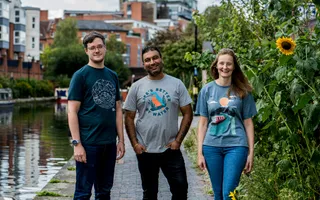 Three adults stand by the canal modelling t-shirts