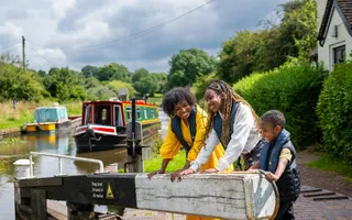Smiling family of 3 working the lock along the canal