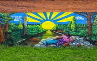 murial of a woman lying down on a canal with the sun rising