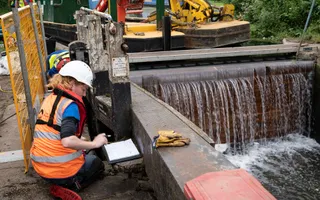 An engineer kneels by a lock gate