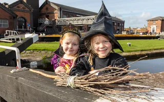 Two children in halloween costumes posing by a lock gate