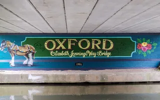 Mural saying 'Oxford: Elizabeth Jennings Way Bridge' with a canal horse and canal-style rose art on the underside of a canal bridge.