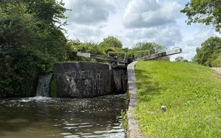 A lock gate rises above a sheer grassy drop