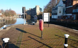 The canal lined with shops and road, with an old mediaeval castle in the distance