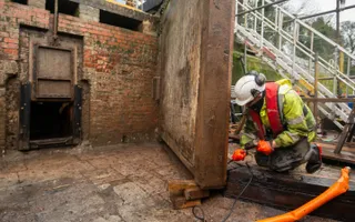 Worker fitting a new lock gate in a drained canal lock