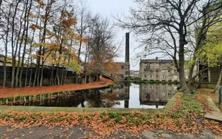 Autumn leaves by the canal in Shipley, with tall buildings in the background