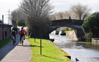 Cyclists on the towpath on a sunny day, travelling along the Beeston Canal