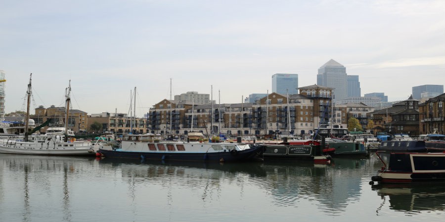 View of Limehouse Basin on Limehouse Cut with boats and flats in the foreground and skyscrapers in the background