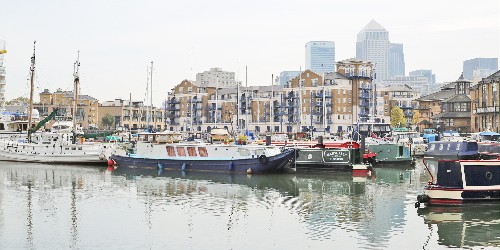 Boats moored in basin with London Docklands in background