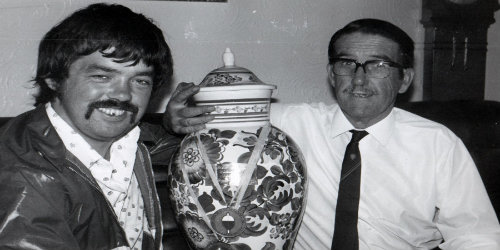 Black and white photo of Ian Heaps with his father Jim holding a trophy
