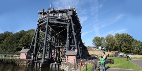 A large black steel structure straddles the canal, for lifting boats from one level to another