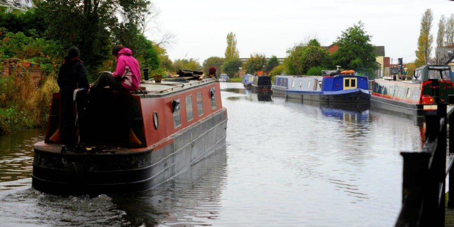 Image of narrowboat cruising past other boats on the canal
