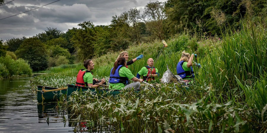 team of four boaters in a canoe picking up rubbish