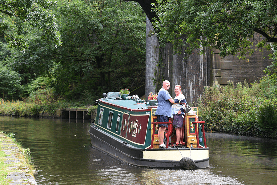 Two people riding a boat along a canal