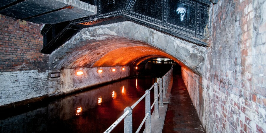 Picture of a dark tunnel with a canal running through it
