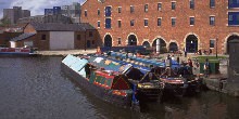 Boats moored by red-brick warehouse on Ashton Canal