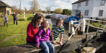 Family sitting on a lock gate watching canal boats