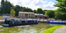 On a sunny day a narrowboat 'Yorkshire Bourne' turns the corner of a canal