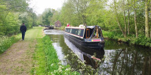 Person walking alongside the canal with a narrowboat on it