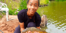 A young person looking happy with a fish they've just caught